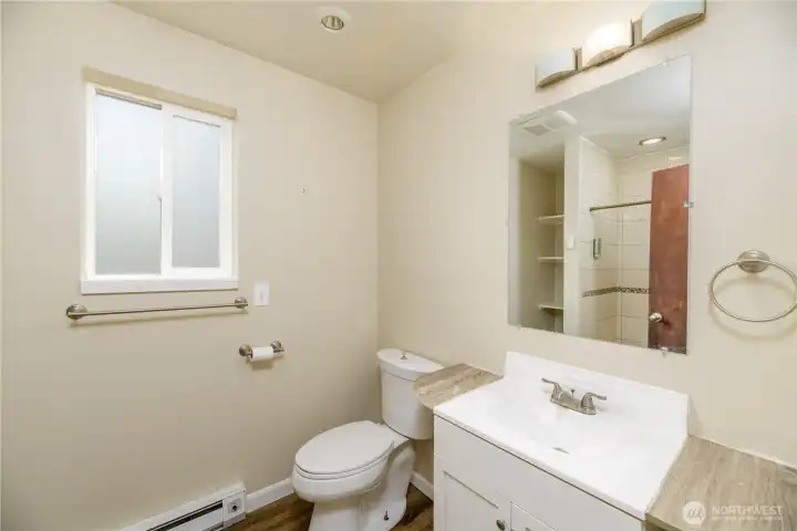 Private en-suite three-quarter bathroom featuring a modern vanity with counter space, updated lighting, and a large mirror.