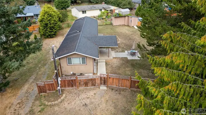 Bird’s-eye view of the back of the home, covered patio, and outdoor entertaining space. The layout emphasizes both privacy and usability, with the home nestled into a generous lot surrounded by trees.