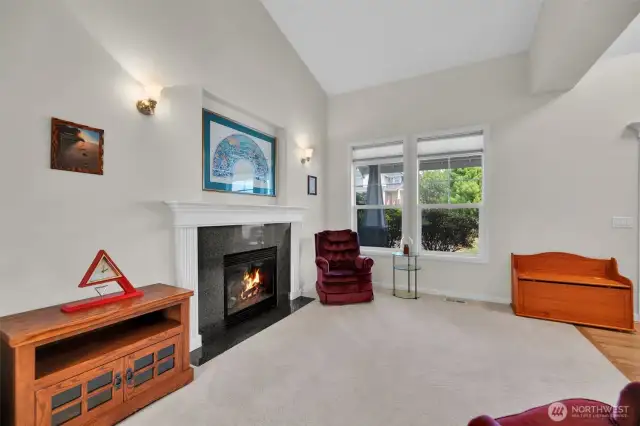 Looking from the dining room toward the living room. Vaulted ceilings, gas fireplace and plush carpeting.