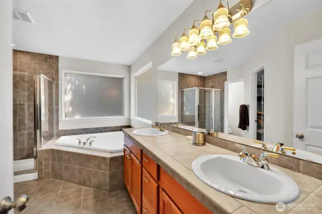 The primary bath with dual vanity sinks, soaking tub, walk in shower, water closet. Tile floors, counters and shower surround make the space. Full length mirror.