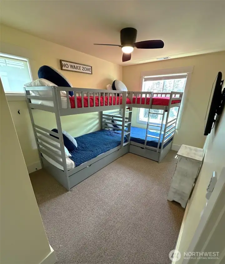 Bright bunkroom has ceiling fan.