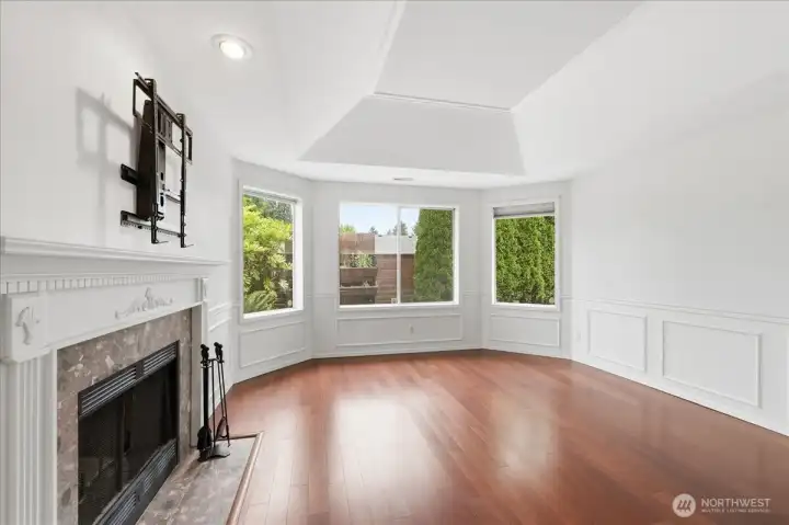 Living room with vaulted ceiling, bay window for extra light, wood burning fireplace and TV mount.