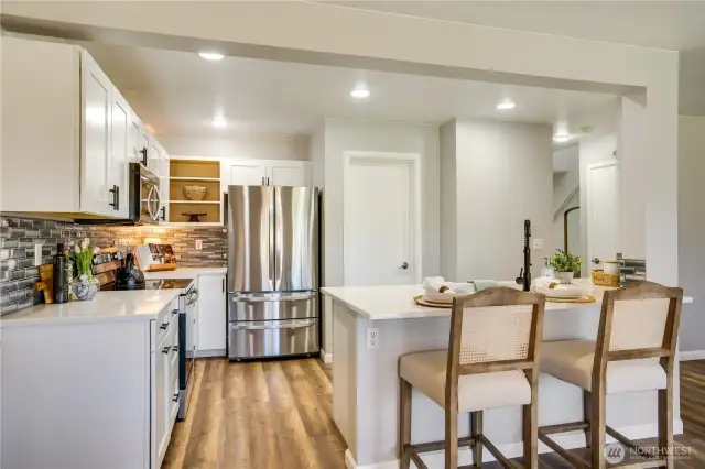 Door to the right of the fridge is the walk-in pantry. Notice how well lit the kitchen is.