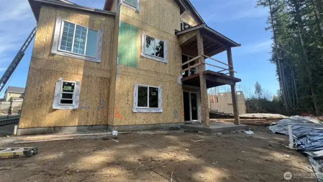 Rear view picture of back of home & yard.  Covered deck going in on main level plus a patio on lower level.
