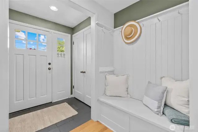 A cozy entry with a mail drop in the closet. A charming bench to sit on and hang your coats.