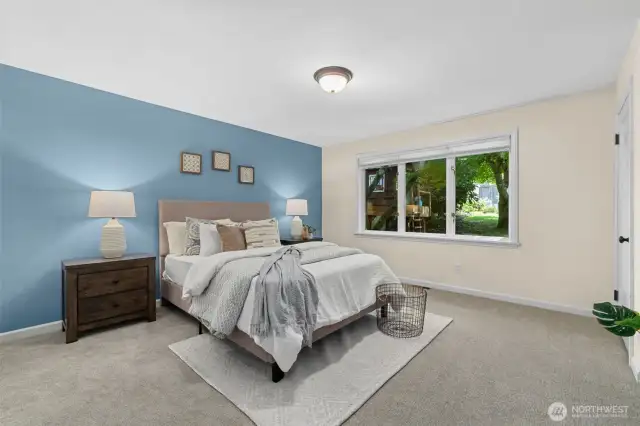 A generous master bedroom with new carpet and a view of the yard.