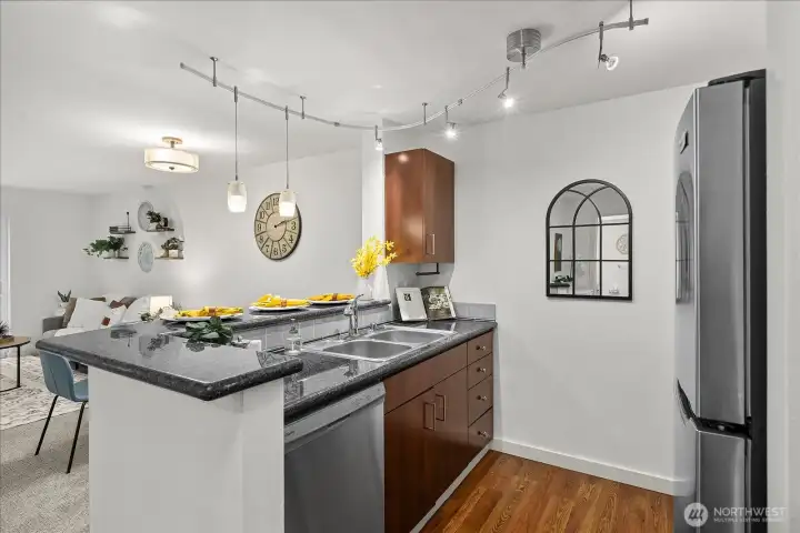 The kitchen features gorgeous dark wood cabinetry, granite countertops, and all stainless steel appliances. Breakfast bar offers additional seating. Dishwasher, range & microwave all convey.