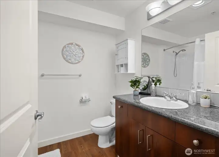 Full bathroom with granite counter and tub with tiled shower surround.