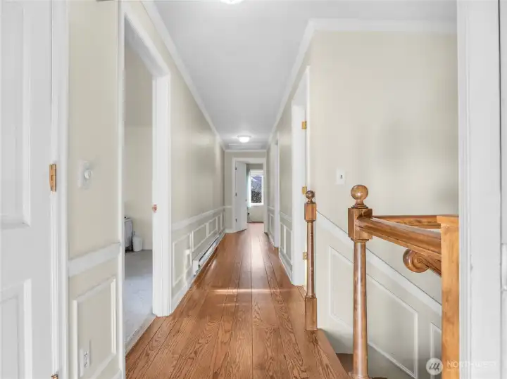 long, hallway with hardwood floors leading to the bedrooms/bathrooms upstairs and the lower level with additional, beds, bath, garage and mud room.