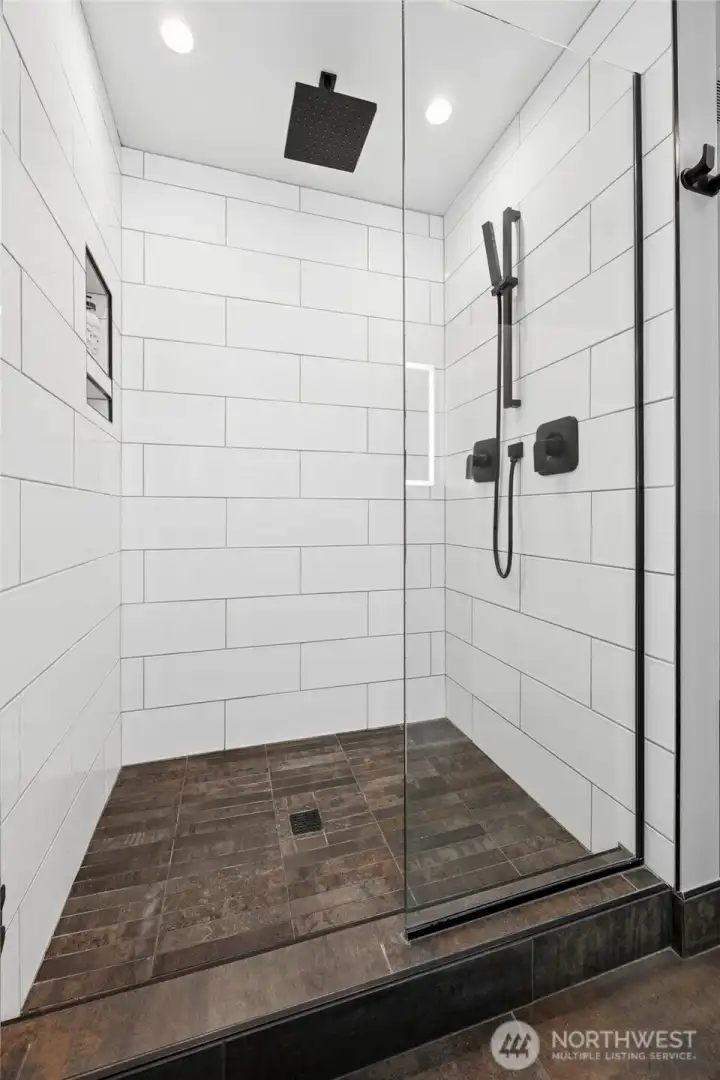 The shower stall has waterfall faucet heads and a built-in caddy for your bath products.