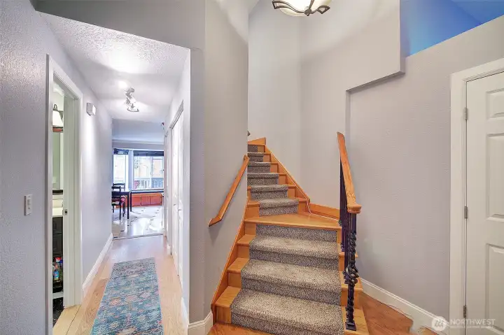 Hardwood stairway with inlaid carpet leads to bedrooms