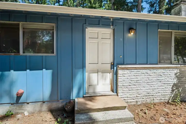 The combination of board-and-batten siding, stacked stone wainscoting, and clean horizontal rooflines creates the kind of curb appeal that fans of vintage architecture instantly recognize. Painted a cheerful shade of blue, the exterior feels welcoming while still offering plenty of opportunity for future personalization. The modest covered entry and original porch light provide a nostalgic nod to the home's era, while the front door serves as the gateway to a property filled with both character and possibility. The combination of board-and-batten siding, stacked stone wainscoting, and clean horizontal rooflines creates the kind of curb appeal that fans of vintage architecture instantly recognize. Painted a cheerful shade of blue, the exterior feels welcoming while still offering plenty of opportunity for future personalization. The modest covered entry and original porch light provide a nostalgic nod to the home's era, while the front door serves as the gateway to a property filled with both character and possibility.