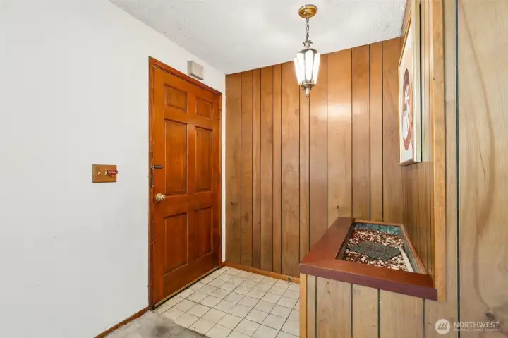 Before you even reach the living room, this home is already telling its story. The foyer greets you with original 1960s design elements that have become increasingly sought-after, including handsome wood paneling with varied-width detailing, an eye-catching vintage light fixture and a built-in planter feature that's pure mid-century magic. The space creates a sense of arrival that's surprisingly uncommon in many rambler floorplans, offering a subtle separation between the entry and main living areas. For buyers who appreciate authentic character, the bones are here. For those dreaming of a fresh transformation, this entry provides a wonderful canvas where original charm and modern updates could coexist beautifully. Before you even reach the living room, this home is already telling its story. The foyer greets you with original 1960s design elements that have become increasingly sought-after, including handsome wood paneling with varied-width detailing, an eye-catching vintage light fixture and a built-in planter feature that's pure mid-century magic. The space creates a sense of arrival that's surprisingly uncommon in many rambler floorplans, offering a subtle separation between the entry and main living areas. For buyers who appreciate authentic character, the bones are here. For those dreaming of a fresh transformation, this entry provides a wonderful canvas where original charm and modern updates could coexist beautifully.