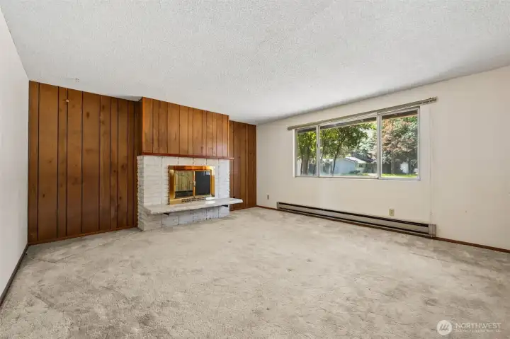 Here's another look at the living room's fantastic proportions and the architectural details that make mid-century homes so appealing. The oversized picture window draws in an abundance of natural light and frames views of the front yard, while the operable side sections provide convenient ventilation when you want to let the fresh Northwest air inside. Across the room, the raised-hearth fireplace adds warmth, character and a touch of retro cool that many buyers spend a fortune trying to recreate. Combined with the original wood paneling and spacious layout, this room feels full of opportunity because the bones are here and they're pretty darn groovy. Here's another look at the living room's fantastic proportions and the architectural details that make mid-century homes so appealing. The oversized picture window draws in an abundance of natural light and frames views of the front yard, while the operable side sections provide convenient ventilation when you want to let the fresh Northwest air inside. Across the room, the raised-hearth fireplace adds warmth, character and a touch of retro cool that many buyers spend a fortune trying to recreate. Combined with the original wood paneling and spacious layout, this room feels full of opportunity because the bones are here and they're pretty darn groovy.