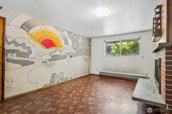 Spanning an entire wall of the family room is a one-of-a-kind vintage mural that feels like it was pulled straight from the late 1960s. Whimsical black-and-white illustrations featuring dancing figures, flowers, trees, mountains and even a leaping fish create a playful backdrop, while a burst of sunrise color steals the show with warm yellow and orange tones emerging over the horizon. Love it or paint over it, it's definitely a conversation starter. The room itself offers great functionality with durable vinyl flooring, a second wood-burning brick fireplace, natural light from the window and plenty of space for gathering. For mid-century lovers, this mural may be the coolest thing in the house. For flippers, it's a blank canvas waiting for its next act. Spanning an entire wall of the family room is a one-of-a-kind vintage mural that feels like it was pulled straight from the late 1960s. Whimsical black-and-white illustrations featuring dancing figures, flowers, trees, mountains and even a leaping fish create a playful backdrop, while a burst of sunrise color steals the show with warm yellow and orange tones emerging over the horizon. Love it or paint over it, it's definitely a conversation starter. The room itself offers great functionality with durable vinyl flooring, a second wood-burning brick fireplace, natural light from the window and plenty of space for gathering. For mid-century lovers, this mural may be the coolest thing in the house. For flippers, it's a blank canvas waiting for its next act.