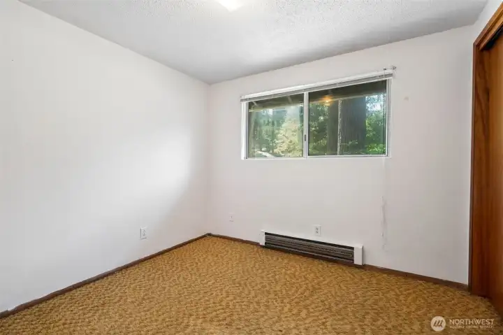 This bedroom enjoys a window overlooking the backyard, bringing in natural light while offering views of the surrounding greenery. Like many homes from this era, you'll find a generously sized closet that provides more storage than many newer homes can claim. The vintage carpeting adds another glimpse into the home's history, while the window blinds allow you to easily customize privacy and light throughout the day. This bedroom enjoys a window overlooking the backyard, bringing in natural light while offering views of the surrounding greenery. Like many homes from this era, you'll find a generously sized closet that provides more storage than many newer homes can claim. The vintage carpeting adds another glimpse into the home's history, while the window blinds allow you to easily customize privacy and light throughout the day.