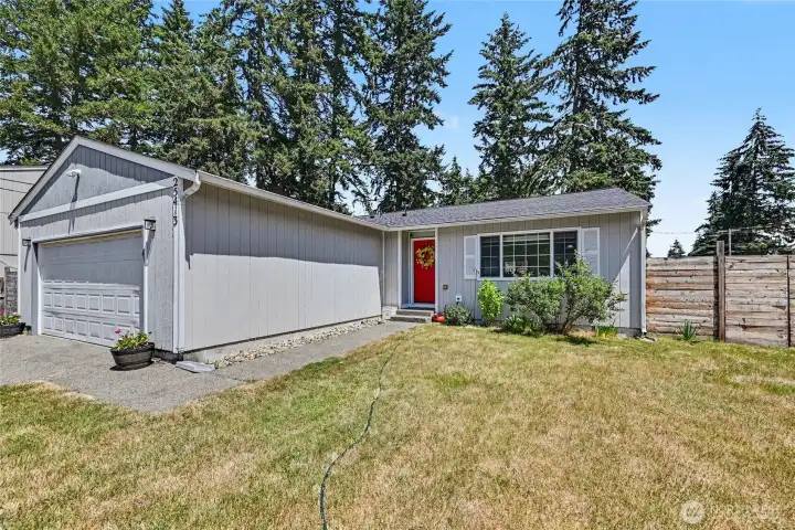 Welcoming curb appeal highlighted by a lush lawn and cheerful red front door.