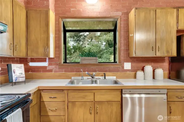 A box window for herbs and houseplants overlooks the back yard and brick brings warmth and texture to the room. A box window for herbs and houseplants overlooks the back yard and brick brings warmth and texture to the room.