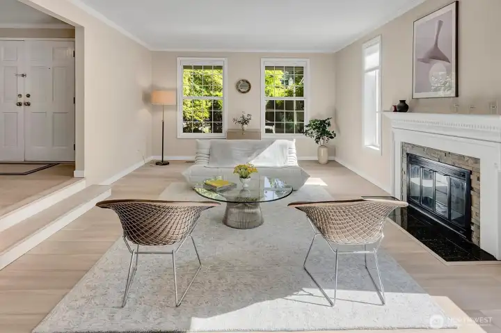 Bright, sunlit living room featuring large front windows that highlight the beautifully landscaped front garden.