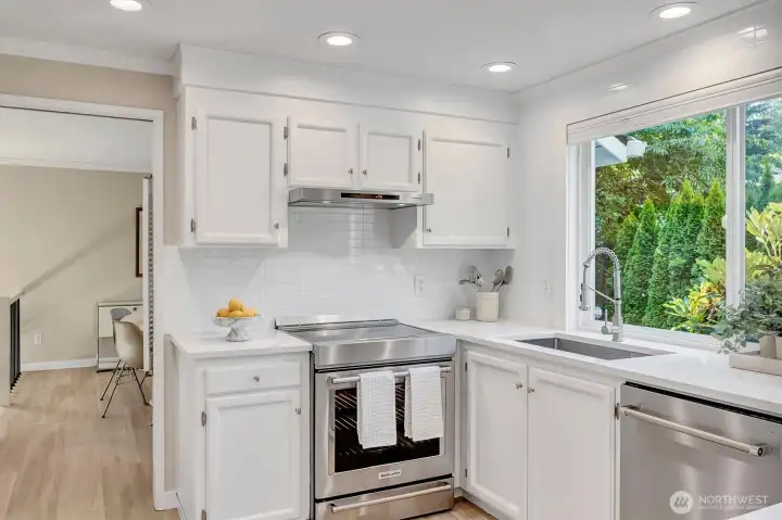 Kitchen featuring a modern stove, stainless steel sink, and dishwasher. This bright, functional space is equipped with updated appliances and ample counter room, making it perfect for meal preparation and entertaining. The layout provides efficient workflow between the sink and cooking areas.