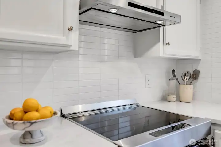 Kitchen features modern stainless steel stove and high-performance ventilation hood.