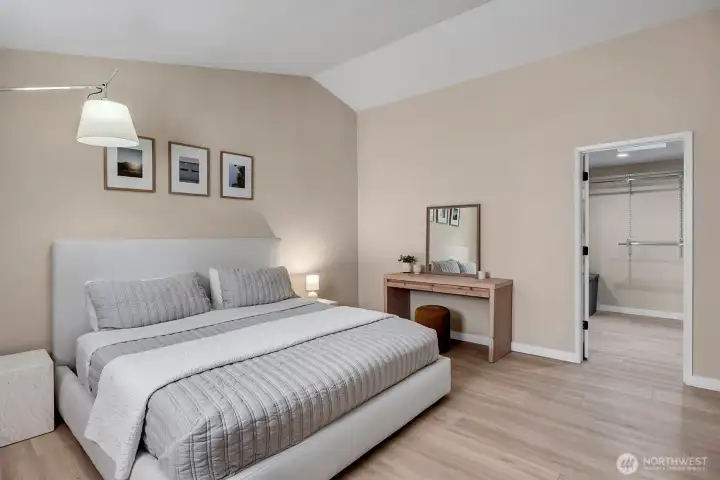 Primary suite features a spacious layout enhanced by a soaring vaulted ceiling, creating an airy and open atmosphere. The room includes a generous walk-in closet, providing ample storage and organization space. This retreat is designed for both comfort and functionality, offering a peaceful sanctuary within the home.