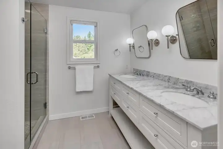 Primary bathroom featuring elegant marble countertops complemented by sophisticated sconce lighting.
