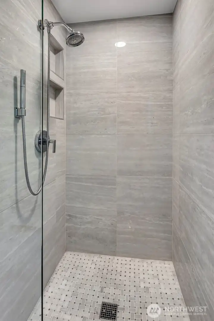 Modern primary bathroom featuring elegant porcelain-tiled shower walls.