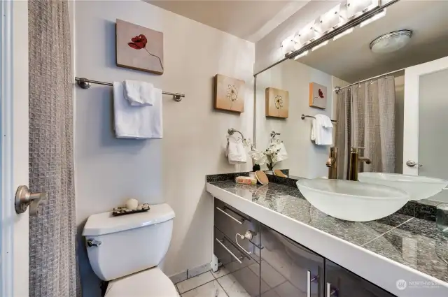 Modern bath with tile floors, plenty of cabinet storage space & full tub & shower.