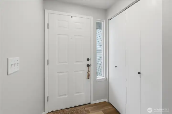 Front entry with updated vinyl plank flooring and paint. North-facing side windows provide consistent, soft, and, indirect light throughout the day. Spacious coat closet upon entry.