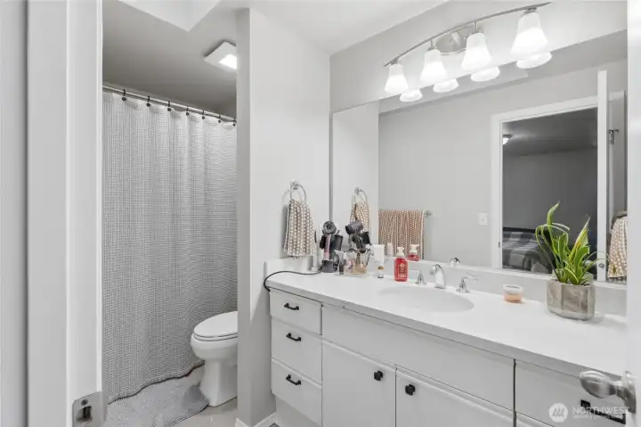 Primary bathroom with updated quartz countertops, undermount sink, and newer fixtures.   Features a tub/shower combo.