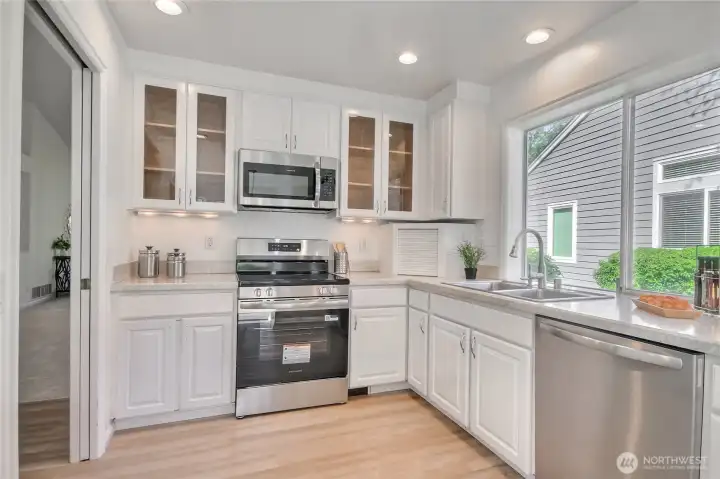 Kitchen features display cabinets, recessed lighting and fresh white cabinets.