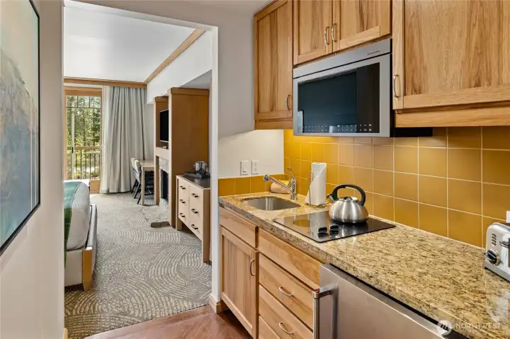 Well-appointed kitchenette with granite counters and ample cabinetry.