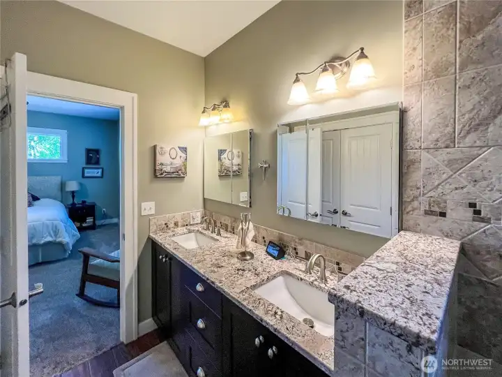 Beautiful primary bathroom with ceramic tile floors, double undermount sinks, granite counters and view back into primary bedroom complete with in floor radiant heat.