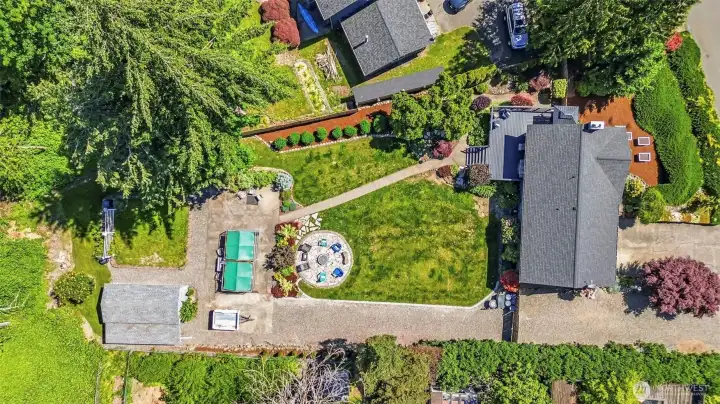 Bird's-eye view of the property displaying the spacious lot, expansive outdoor living areas, garden space, RV parking, and detached outbuilding.