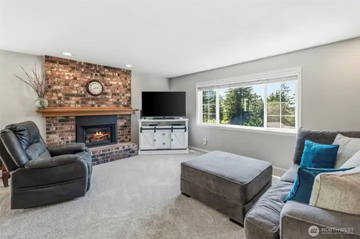 Comfortable living room with large picture window, abundant natural light, gas fireplace, and peaceful territorial views.