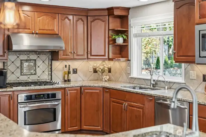 Beautiful kitchen with custom wood cabinetry, tile backsplash, stainless steel range, and views of the backyard.