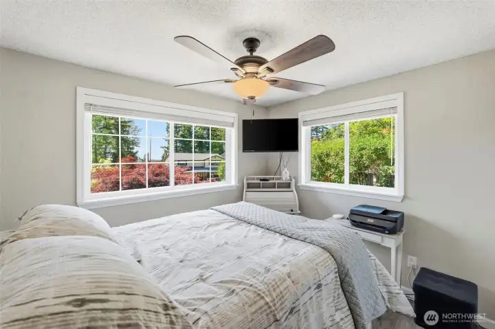 Spacious 3rd bedroom featuring large windows, peaceful backyard views, ceiling fan, and plenty of room for a bedroom set.