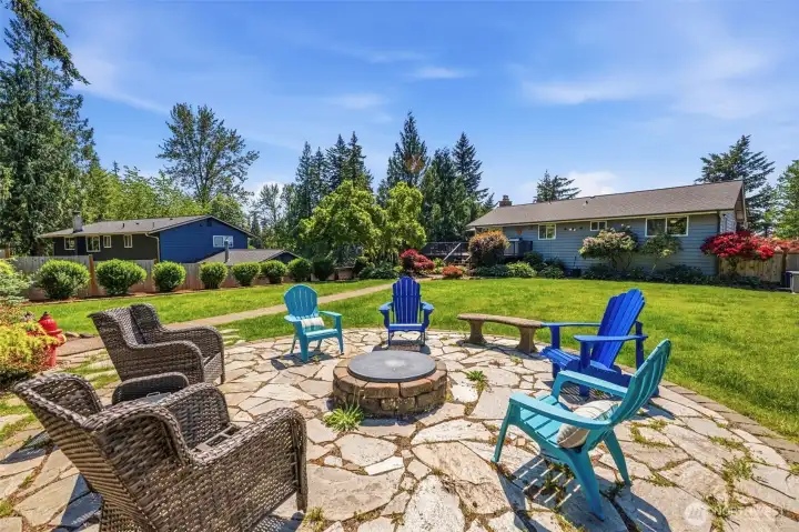 Custom fire pit patio surrounded by lush landscaping creates the perfect setting for outdoor entertaining and relaxing Enumclaw evenings.