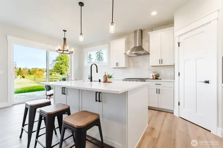 An entertainer’s island with bar seating and extra storage opens to the patio and backyard for easy indoor-outdoor living.