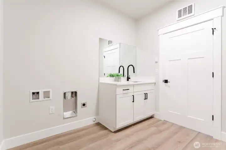 Enter the garage through the oversized laundry room with sink.