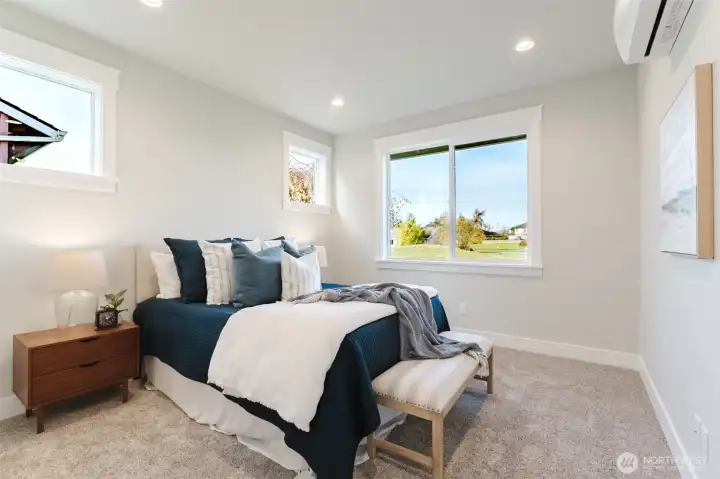 Just off the living room is the main-floor primary suite with soft carpet, ductless mini-split for comfort, and a large window looking out over the greens.