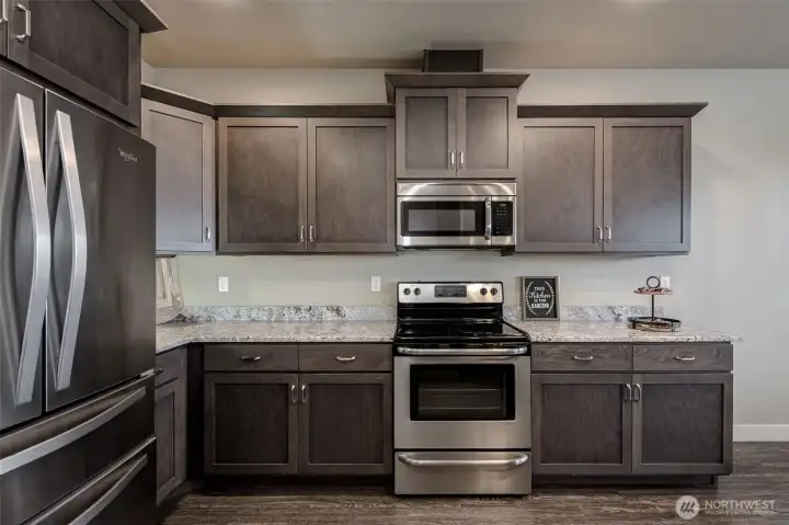 Bright, functional kitchen featuring stainless steel appliances, abundant cabinetry, generous counter space, and a peninsula with bar seating.