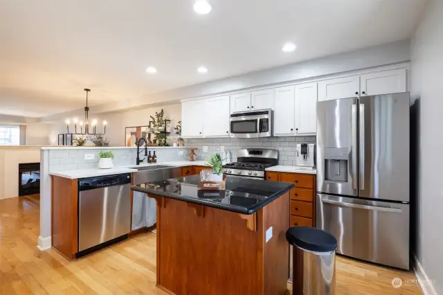 Kitchen has new quartz countertops, tile backsplash, kitchen sink, and refrigerator.