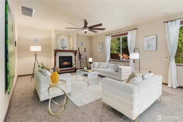 Light-filled, this oversized living room features a cozy gas fireplace and soaring ceilings anchored by two tall picture windows that frame serene views of the private yard and lush greenbelt. A perfect space for gatherings or quiet moments at home