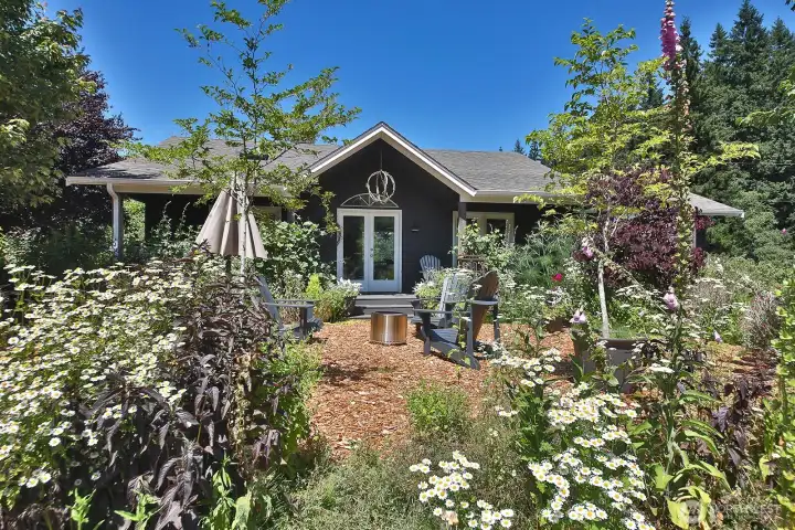 South/front of your home. The surrounding gardens create a lovely private gathering space. The covered front porch is spacious enough for tables, chairs and garden work space. French doors (straight ahead) open to the dining/kitchen area.