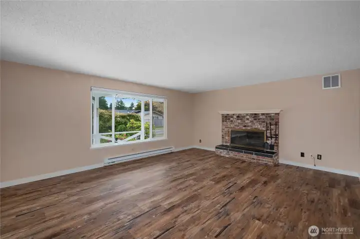This inviting living room boasts a large picture window that fills the space with natural light and a charming brick fireplace as the perfect focal point for relaxing or entertaining.