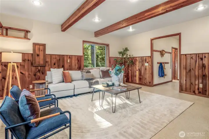 The family room welcomes you with warm wood tones, exposed beams, and flexible space for relaxing or entertaining. Mudroom and back entry are located to the right.