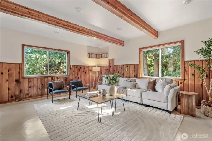 Another view of the family room. The wood walls and open beam ceilings make it feel like a lodge. Imagine all the fun you can have here! The two windows add light and offer beautiful views of nature.