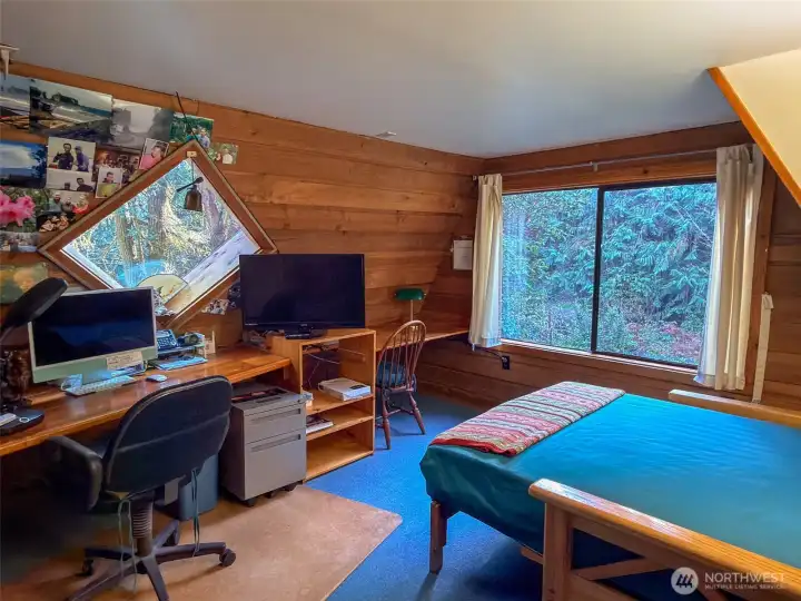 Office in the loft with a skylight, large wood wrapped window and guest or day bed.